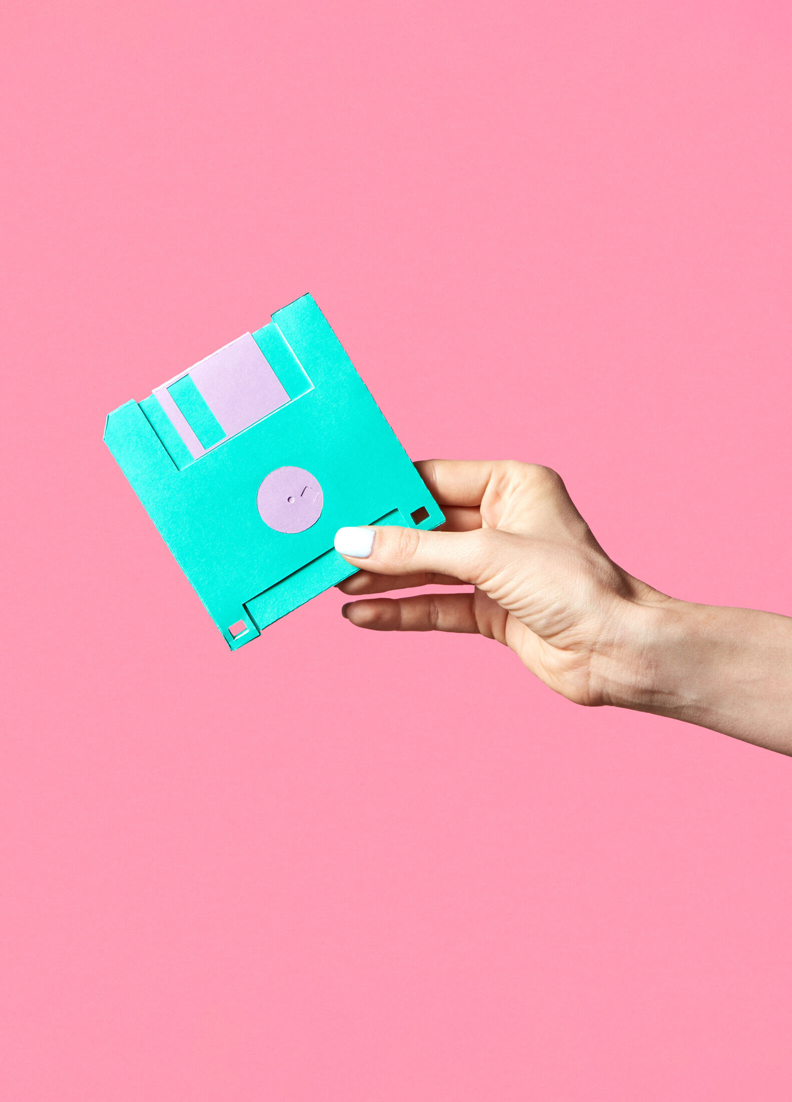 Isolated hand holding a floppy disk in front of a bright background