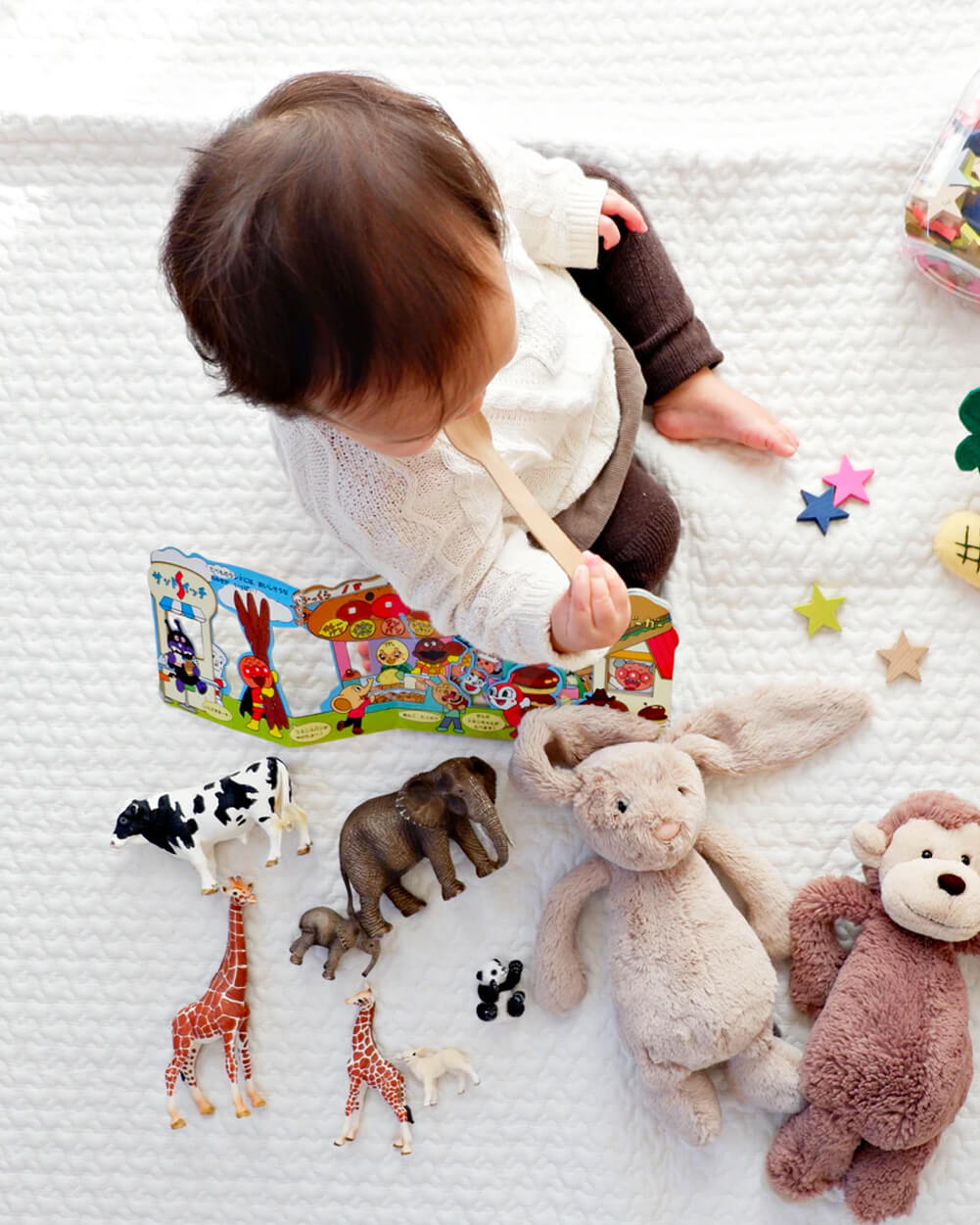 Infant sitting on a blanked playing with toys